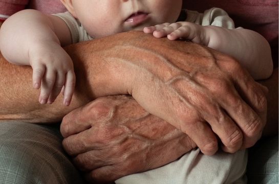 Fotografie: Ein Baby wird von Händen gehalten