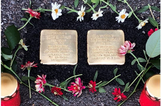 Fotografie - eingebaute Stolpersteine mit Kerzen und Blumen geschmückt