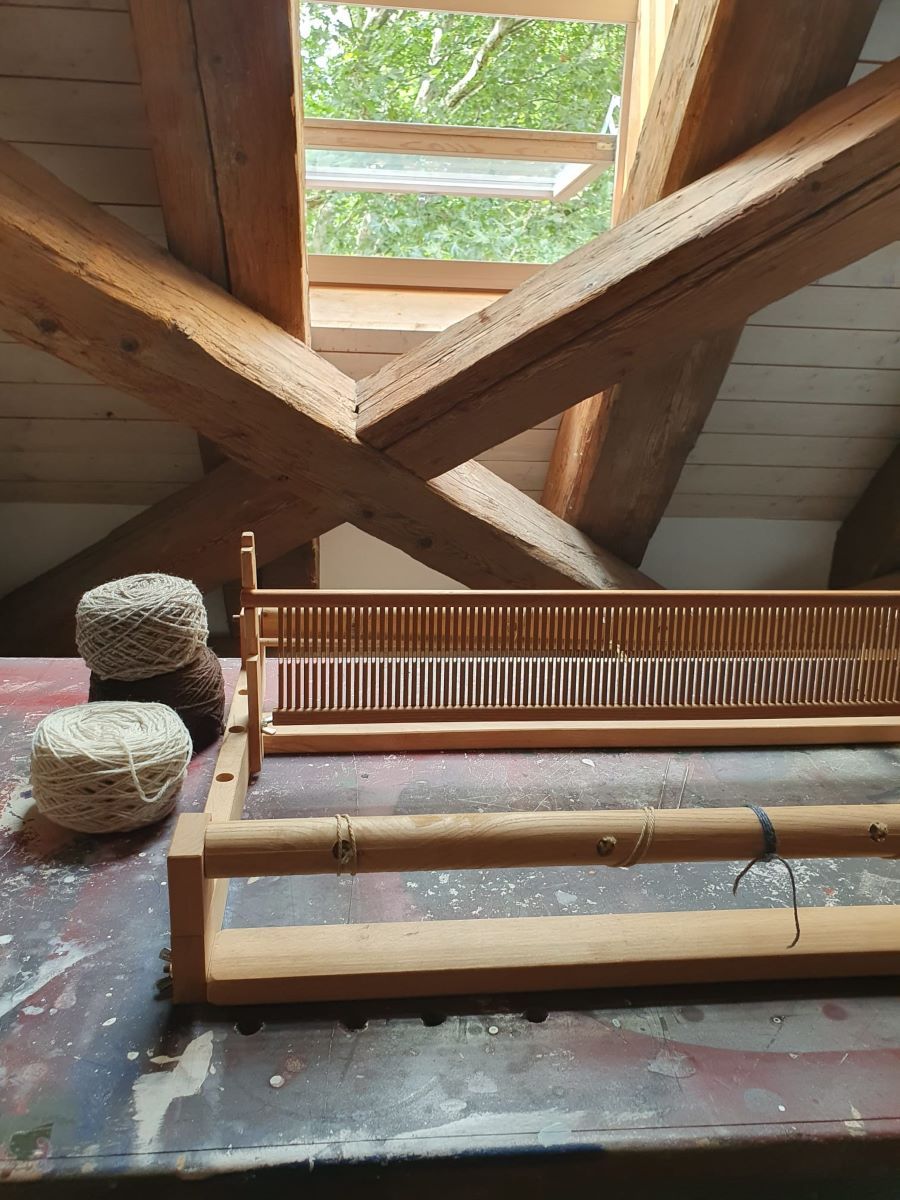Fotografie – Webstuhl auf Tisch im Dachgeschoss mit geöffnetem Dachfenster