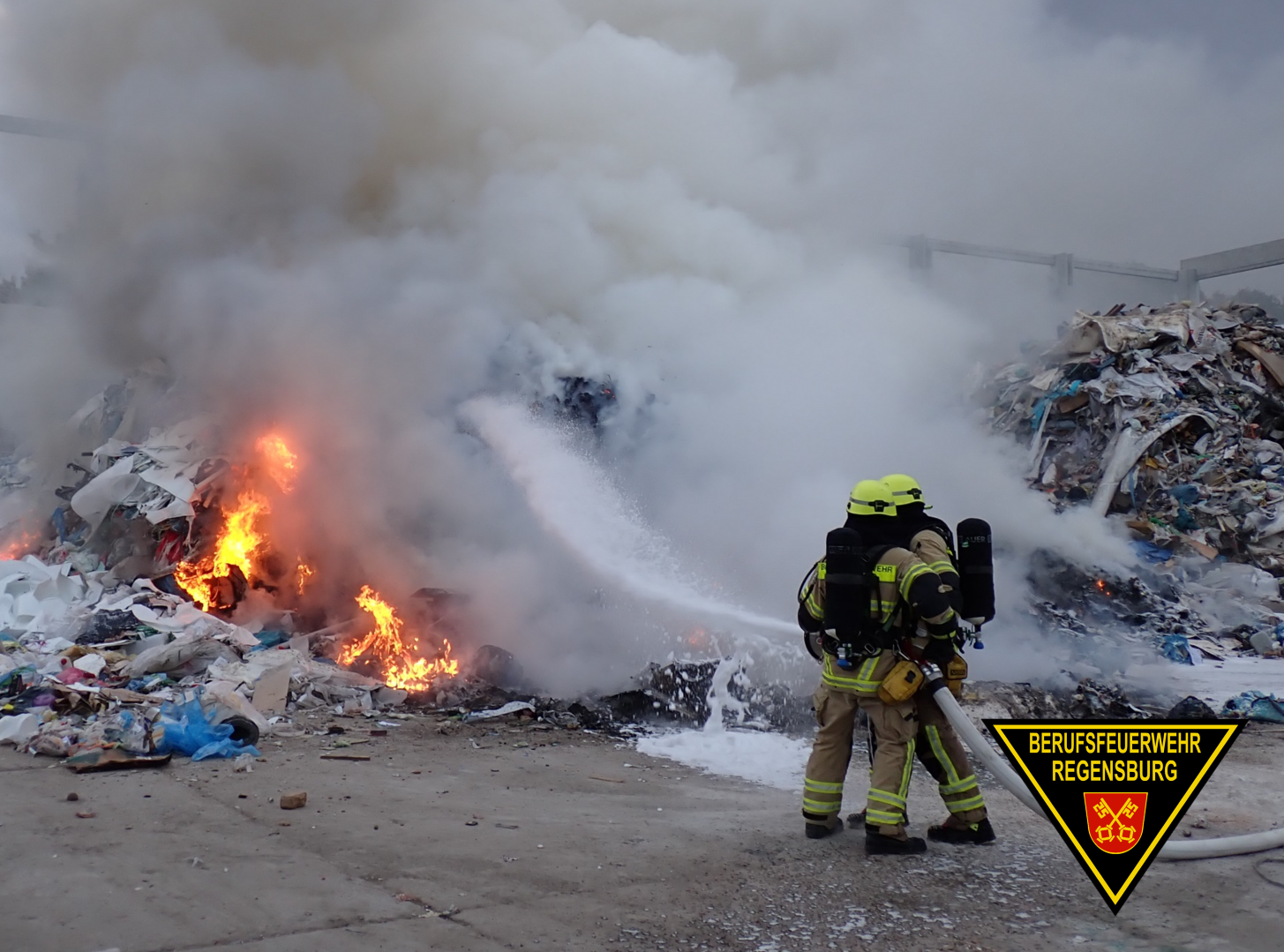 Feuerwehrleute löschen brennenden Müllhaufen