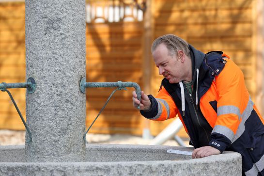 Ein Mann in Arbeitskleidung begutachtet einen Brunnen. (C) Bilddokumentation Stadt Regensburg