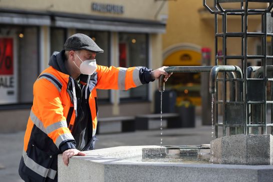 Eine Person steht an einem Brunnen.