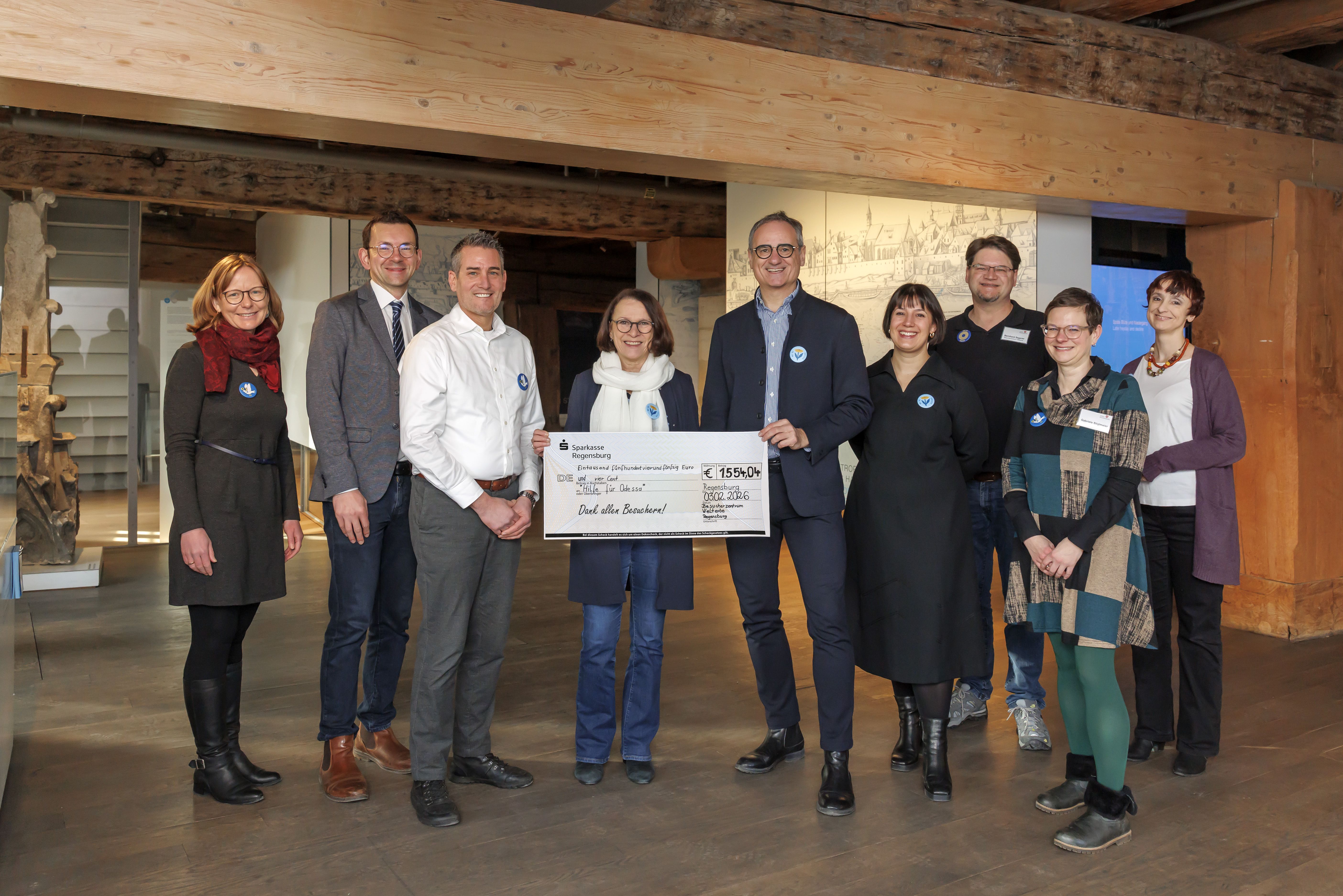 Fotografie – Oberbürgermeisterin Getrud Maltz-Schwarzfischer und Sandra Schneider vom Hauptamt der Stadt Regensburg freuen sich über die Spende, die von Kulturreferent Wolfgang Dersch, Lorenz Baibl, Leiter des Amtes für kulturelles Erbe, Welterbekoordinator Dr. Matthias Ripp und dem Team des Besucherzentrums Welterbe, Susanne Niederleitner, Bernhard Segerer und Gabi Stiglmeier sowie der Projektleitung Janina Rummel übergeben wurde.