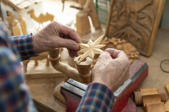 Fotografie: Zwei Hände halten einen Holzstern über einer Werkbank.