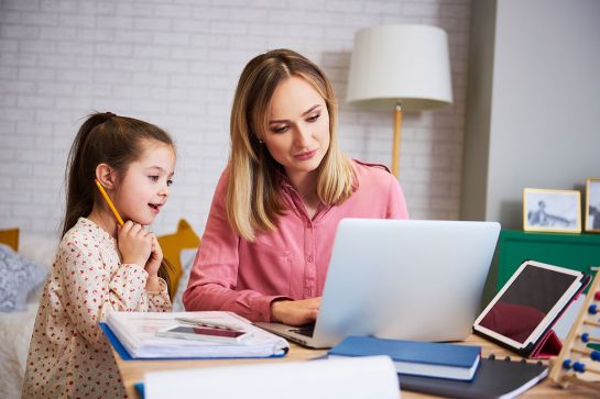 Fotografie: Mutter sitzt mit Tochter vor Laptop im Homeschooling