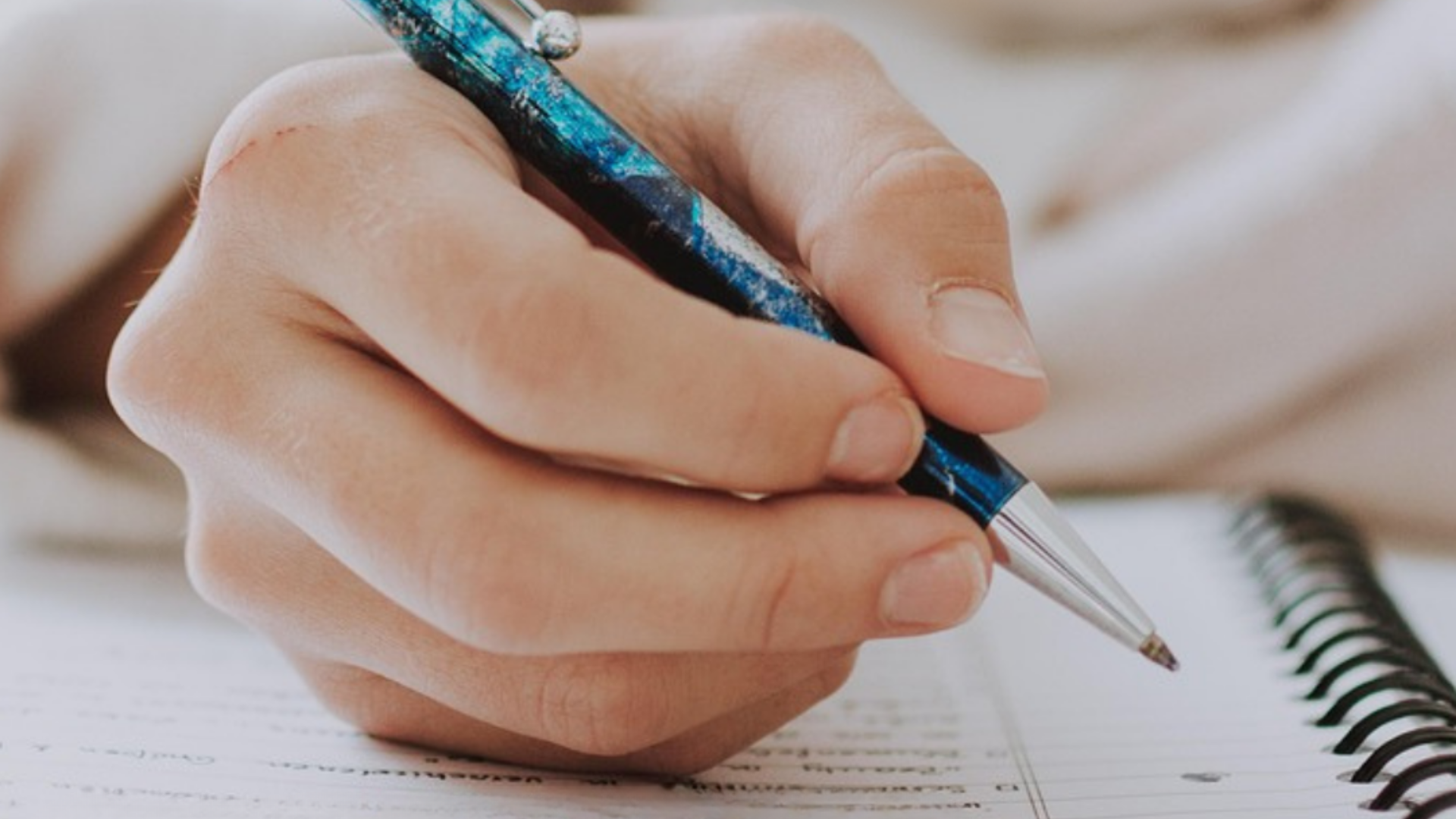 auf dem Fotos sieht man eine Großaufnahme einer Hand die einen Stift hält 