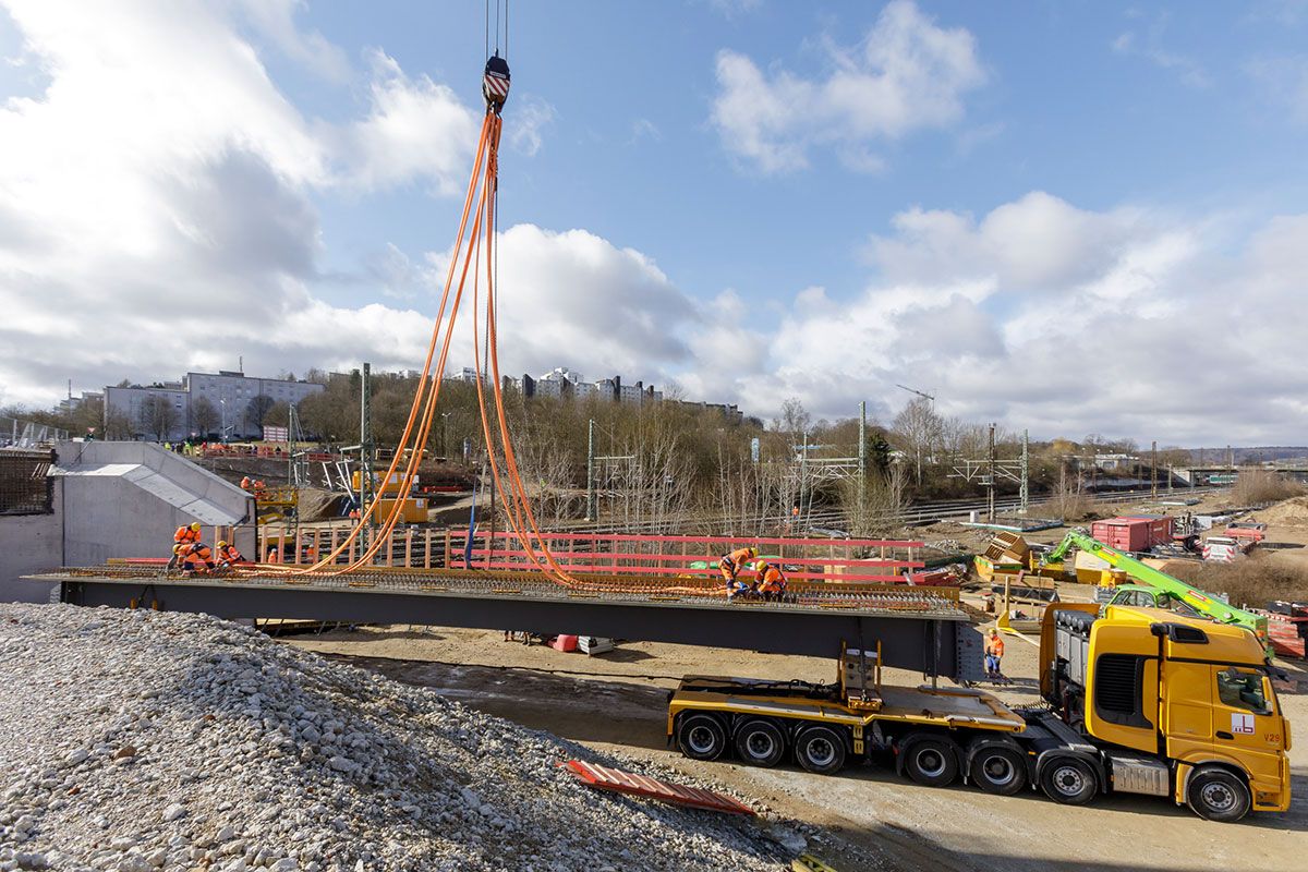 Neubau Klenzebrücke - Fotografie - Einhub Verbund-Fertigteilträger - auf dem Bild ist zu sehen, wie ein Verbundfertigteilträger auf einem Lkw zur Montage vorbereitet wird; Kran-Hebebänder werden am Fertigteil angebracht.