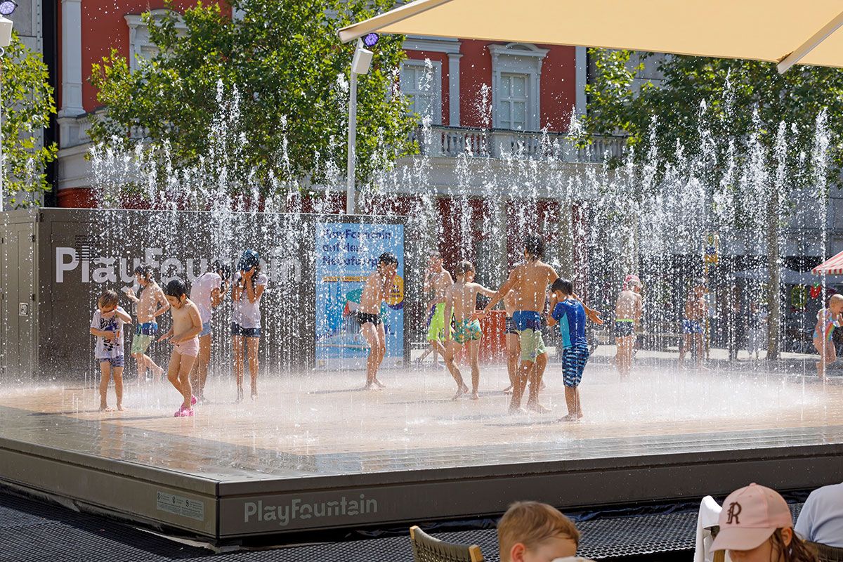 Kinder im Sommer spielen in einem Brunnen.