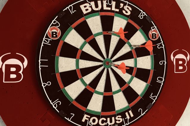 Es ist eine Dartscheibe mit drei Dartpfeilen zu sehen.
