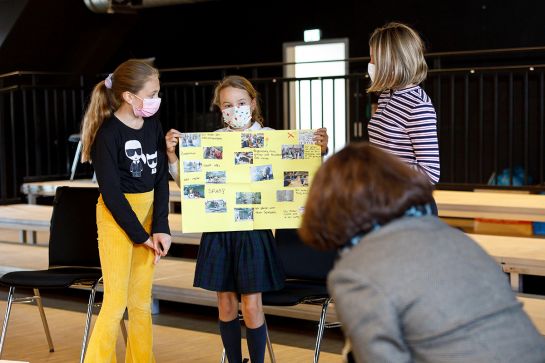Fotografie – drei Mädchen präsentieren Oberbürgermeisterin Gertrud Maltz-Schwarzfischer ein Plakat mit Fotos der letzten Aktionen (C) Bilddokumentation Stadt Regensburg