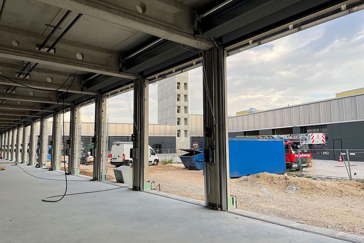 Fotografie - Blick aus der Fahrzeughalle in den Hof. Inzwischen ist der Betonboden fertig und auch die Tore wurden bereits montiert.