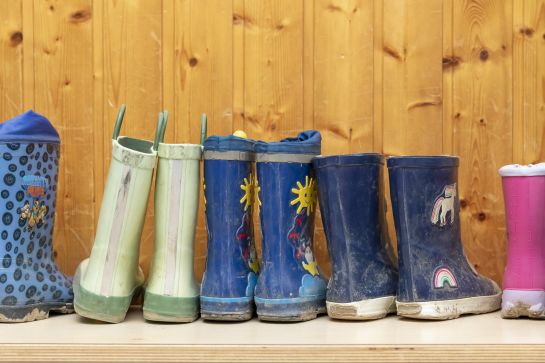 Fotografie: Kinder-Gummistiefel stehen nebeneinander auf einer Bank.