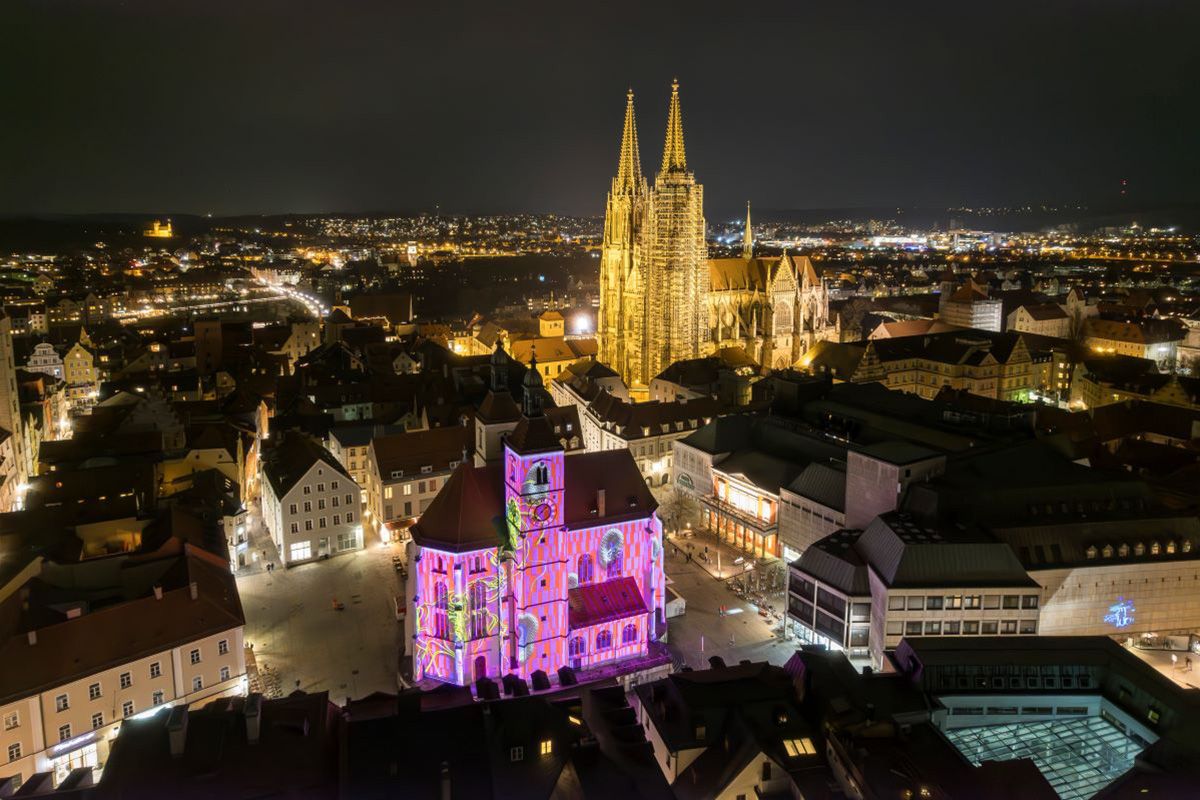 Fotografie: Neupfarrkirche beim RE.LIGHT Festival 2024 in pink beleutet, von oben betrachtet mit Dom im Hintergrund