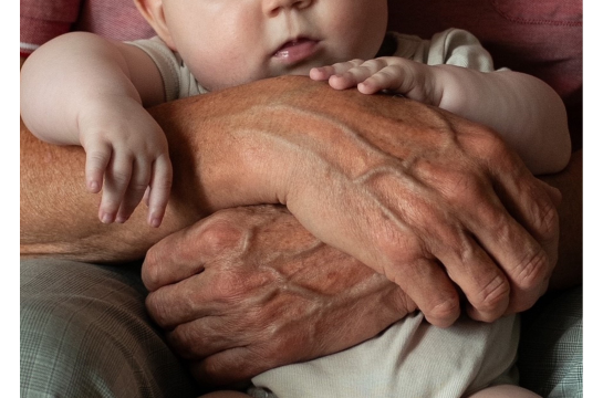 Fotografie: Ein Baby wird von Händen gehalten