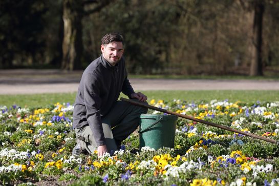 Fotografie: Matthias Peter kniet in einem Blumenbeet (C) Bilddokumentation Stadt Regensburg