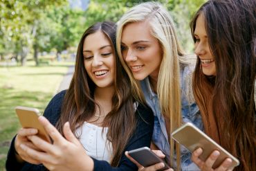 Fotografie: Drei junge Frauen schauen in ein Smartphone.