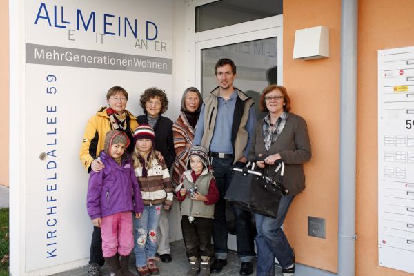 Seniorenportal - generationsübergreifendes Wohnprojekt - eine Gruppe von Bewohnern am Eingang zu einem der Wohnhäuser