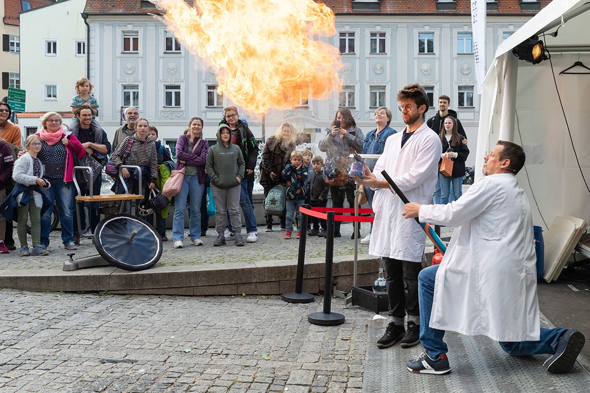 Fotografie: Zwei Wissenschaftler in weißen Kitteln experimentieren mit Feuer.