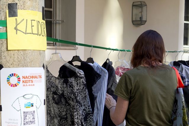 Eine Frau beim Durchstöbern von Kleidern, die bei der Kleidertauschparty im Rahmen der Nachhaltigkeitswoche 2021 im Innenhof des Regensburger Thon-Dittmer-Palais stattfand.