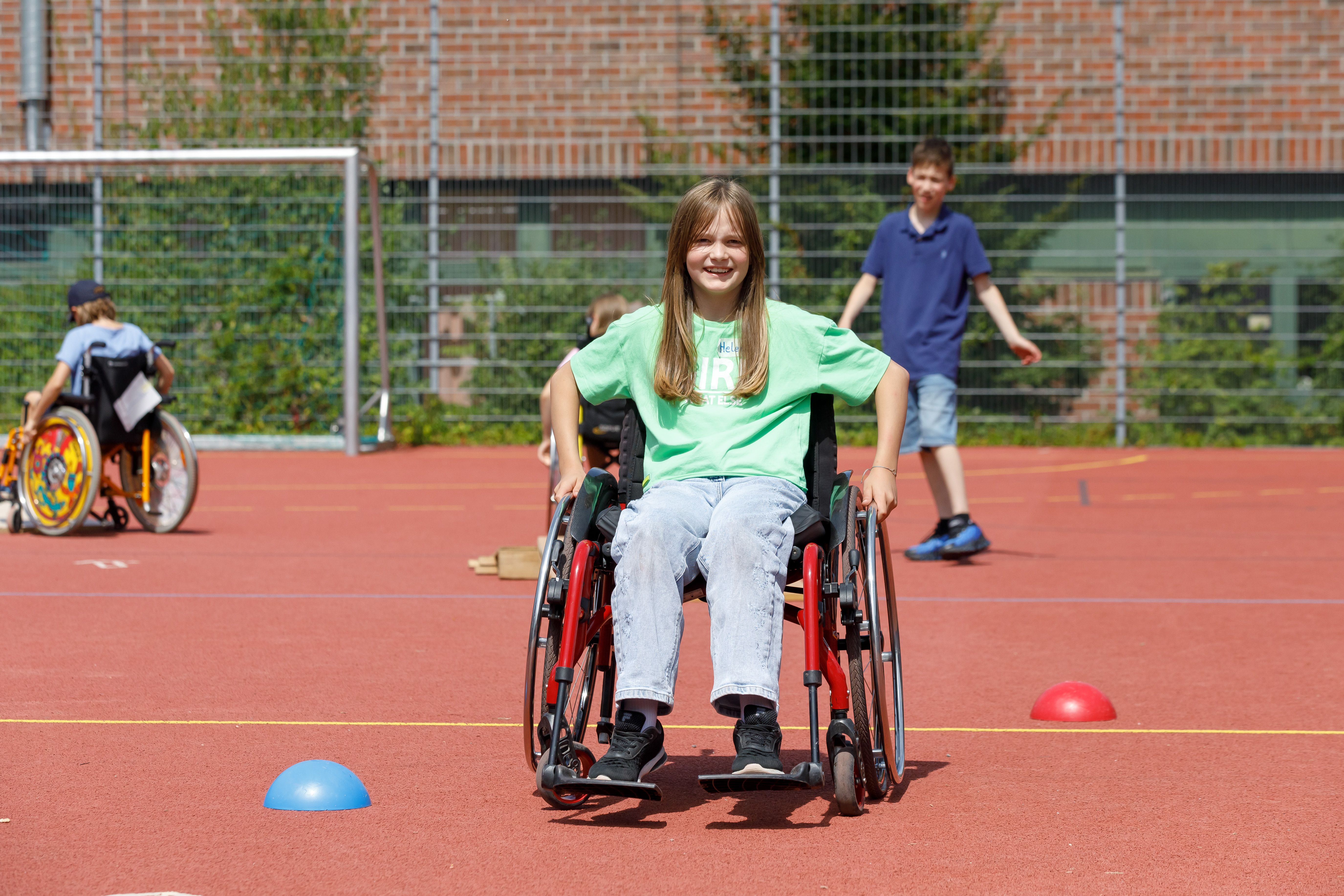 Fotografie: Ein Mädchen im Rollstuhl auf dem Sportplatz