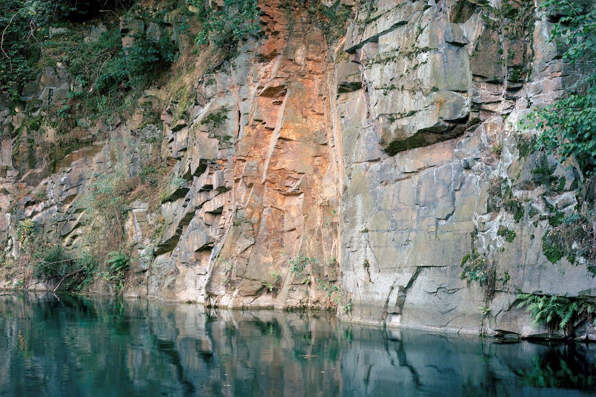 Fotografie - Blick vom Wasser auf eine Felswand 