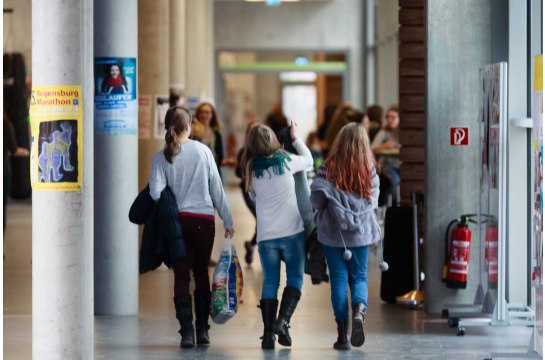 Fotografie: Drei Mädchen gehen einen Schulflur entlang.