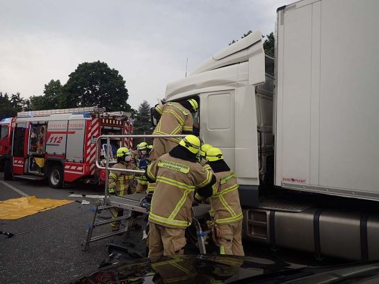 Fotografie: Feuerwehrbeamte vor einem verunfalltem Lastwagen auf der Autobahn.