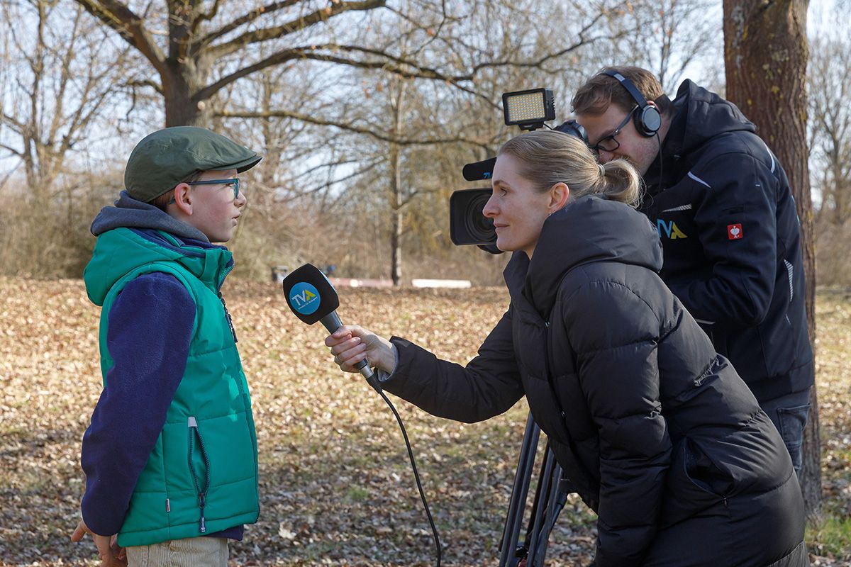 Fotografie - Ein Kinderbeirat spricht in ein TVA-Mikrofon und wird mit Kamera gefilmt