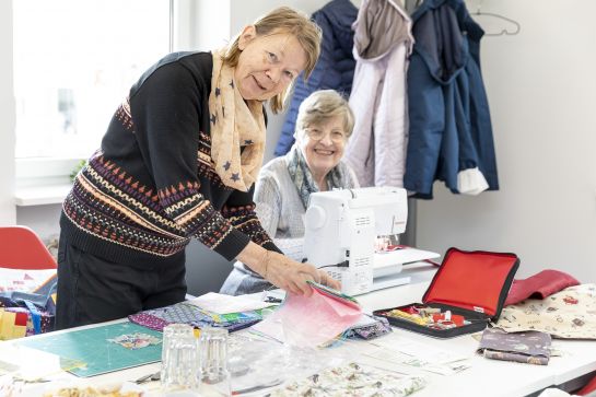 Fotografie: Zwei Seniorinnen arbeiten an einer Nähmaschine.