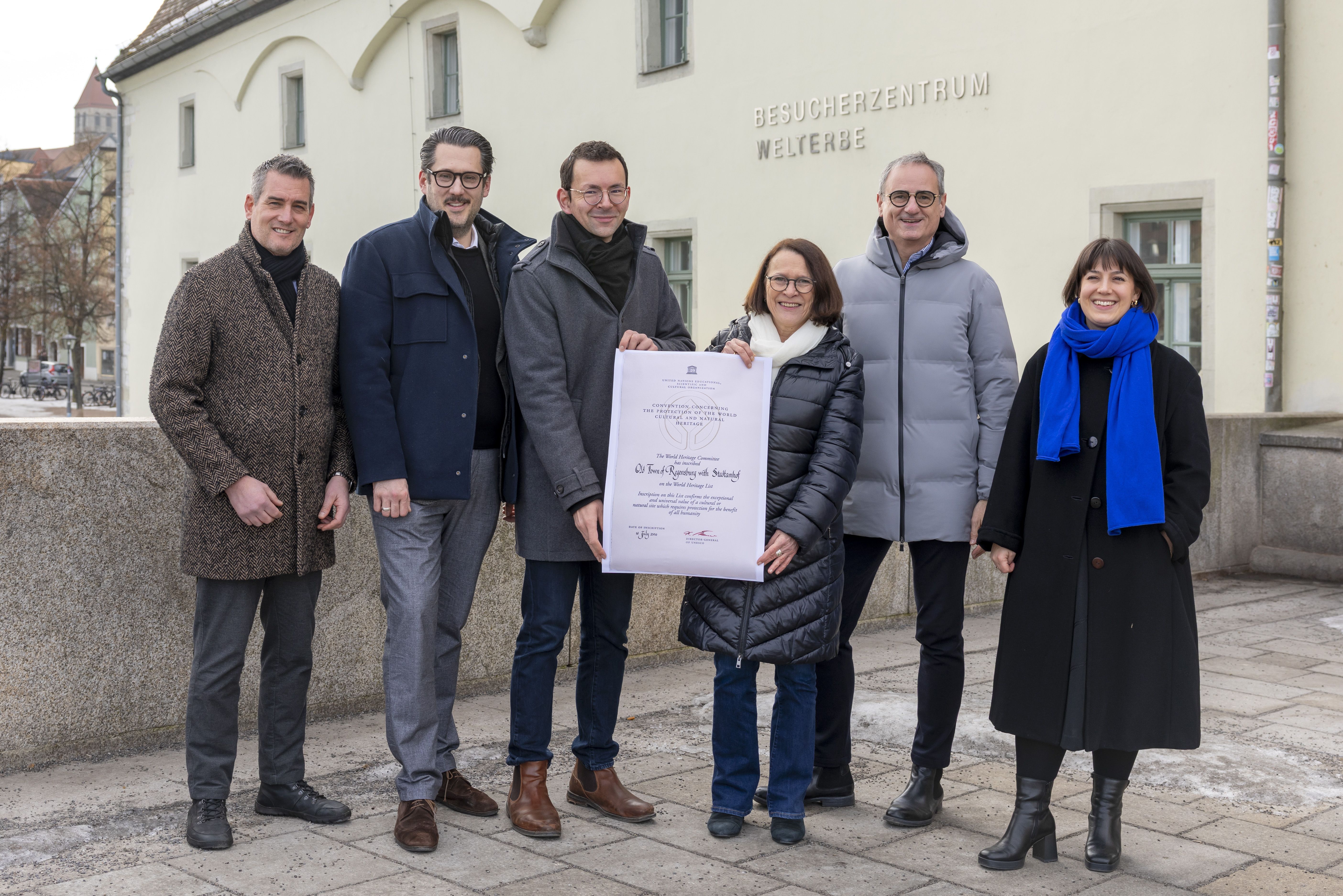 Fotografie – Regensburg feiert das Welterbe-Jubiläum mit der bundesweiten Eröffnung des UNESCO-Welterbetages 2026 in Regensburg. Gruppenbild der Beteiligten: (v.l.n.r) Welterbekoordinator Dr. Matthias Ripp, Leiter der Regensburg Tourismus GmbH Jakob E. Reitinger, Leiter des Amtes für kulturelles Erbe Lorenz Baibl, Oberbürgermeisterin Gertrud Maltz-Schwarzfischer, Kulturreferent Wolfang Dersch und Janina Rummel, Projektleitung des Welterbetages 2026.