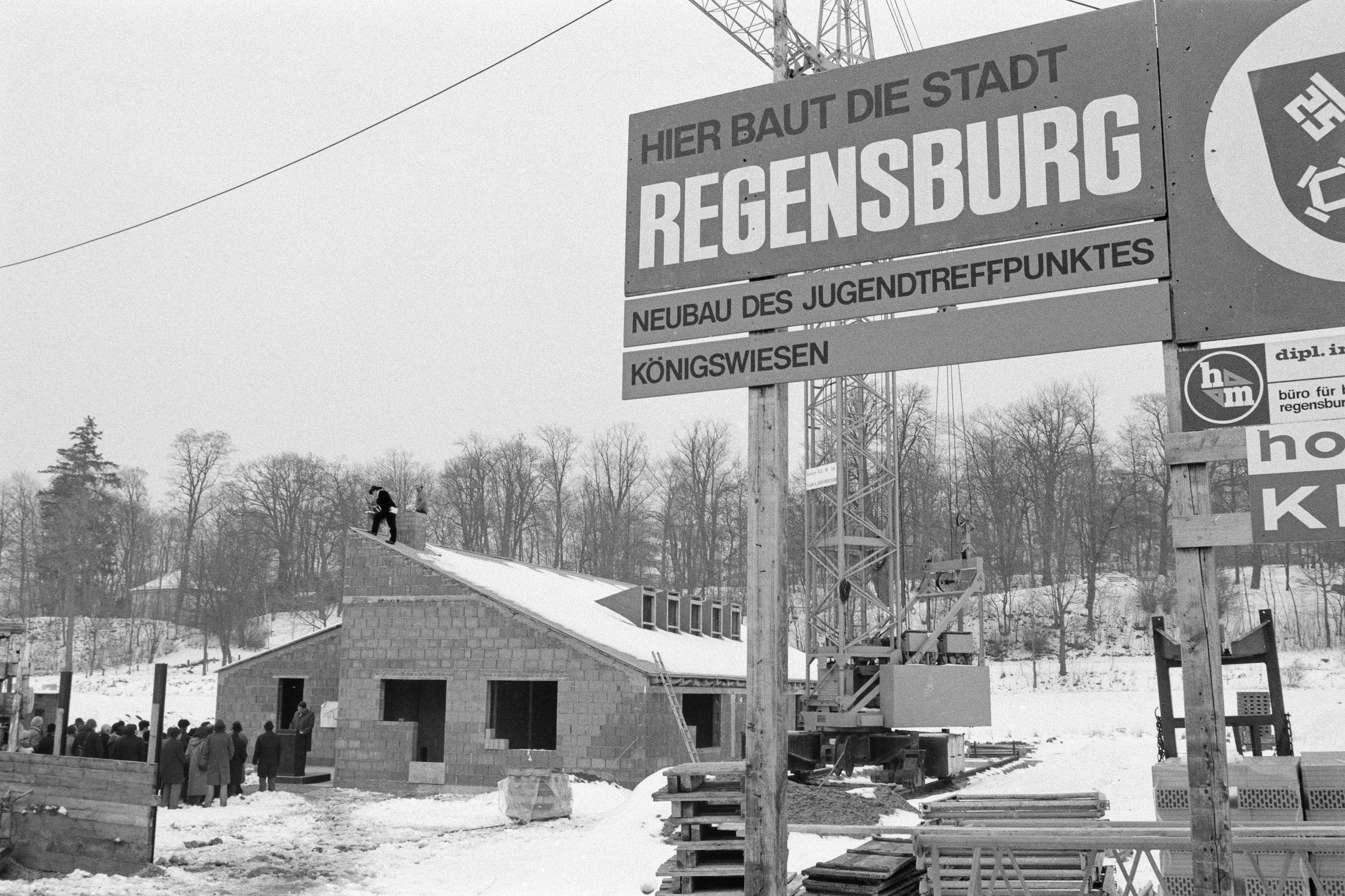 "Hier baut die Stadt Regensburg" steht auf einem großen Schild vor dem Rohbau des Jugendzentrums Königswiesen.