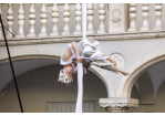 Fotografie – eine weißgekleidete Akrobatin turnt kopfüber in der Luft