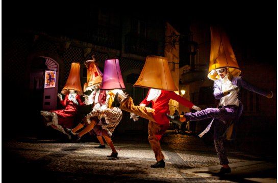 Fotografie: Tanzenden Menschen tragen Lampenschirme auf dem Kopf.