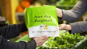 Zwei Menschen halten einen Papiertüte mit der Aufschrift "Aus der Region"