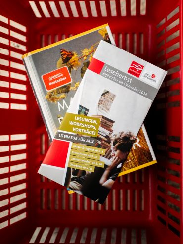 Fotografie: Programmhefte zum Leseherbst liegen in einem roten Korb.