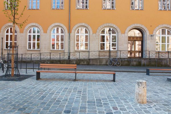 Fotografie - Holzbank vor gelbem Gebäude
