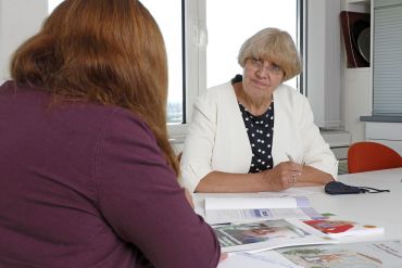 Fotografie: Zwei Frauen sitzen sich an einem Tisch gegenüber (C) Bilddokumentation Stadt Regensburg Altenpflegeeinrichtungen 2