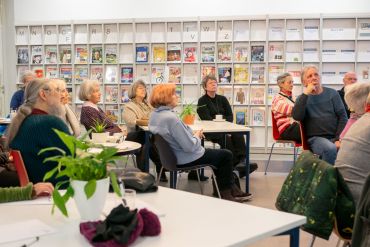 Fotografie: Senioren sitzen an Tischen in der Stadtbücherei