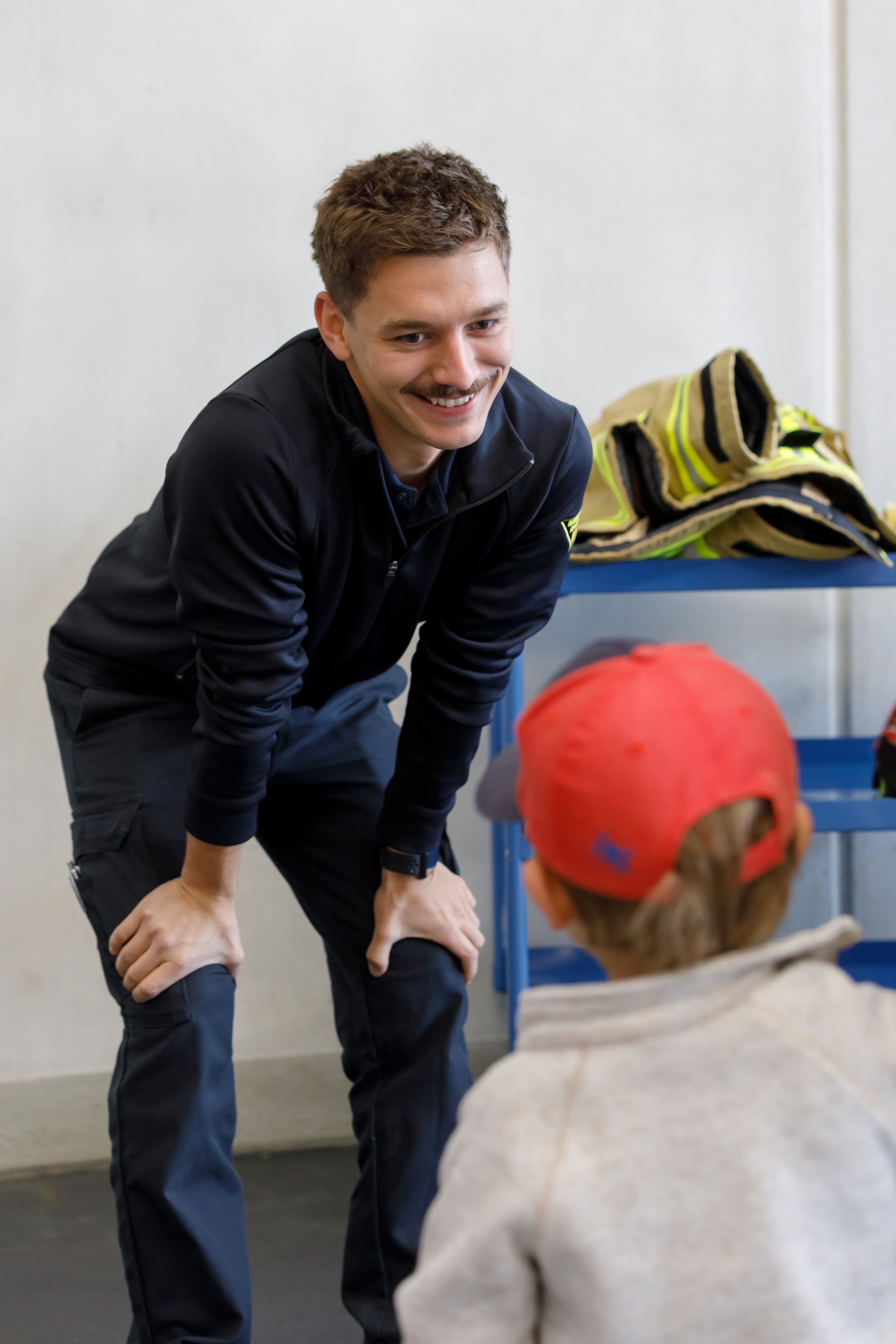 Fotografie: Ein Feuerwehrmann im Gespräch mit einem kleinen Jungen