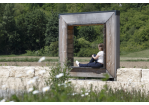 Fotografie: Frau sitzt in hölzernem Kunstwerk im Sandfrauenpark