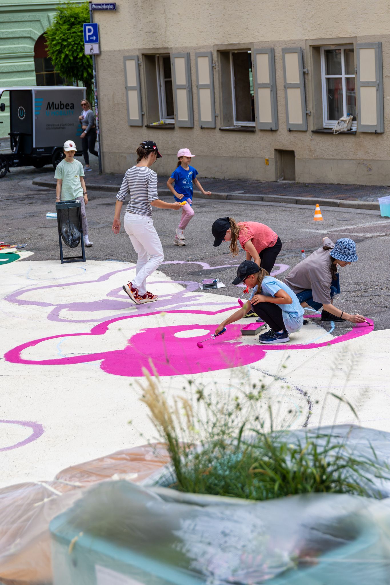 Fotografie – Kinder malen das Bodenkunstwerk im Obermünsterviertel.