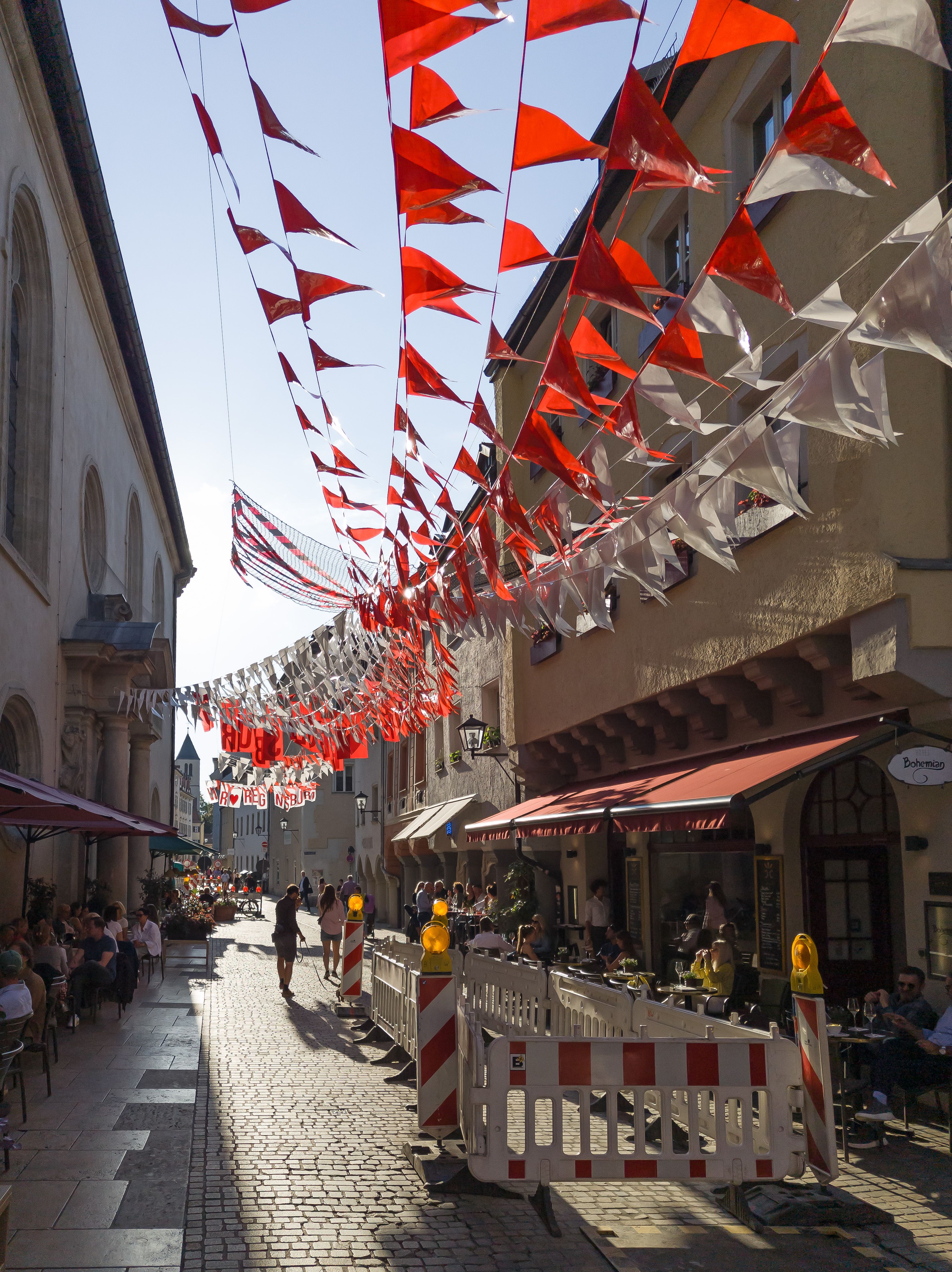 Fotografie: Blick in die Gesandtenstraße im Sonnenschein mit Menschen auf Freisitzen