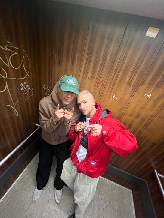 Suffbeidl steht mit einem Freund in einem vollgetagten Fahrstuhl.