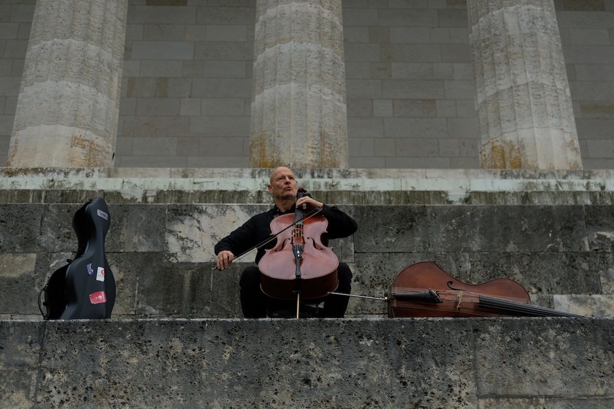 Fotografie – Jean de l´Aire, aka Hans Schanderl sitzt auf den Stufen der Walhalla und spielt Violoncello 