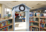 halbkreisförmiges Bücherregal mit hellblauem Tor, darauf ist ein Bullauge montiert und führt in die neugestaltete Kinderbücherei Burgweinting (C) Stefan Effenhauser