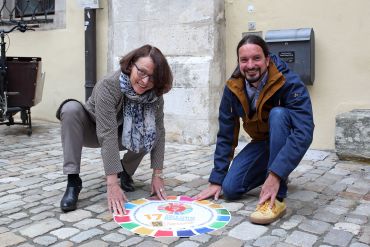 Fotografie: Oberbürgermeisterin Gertrud Maltz-Schwarzfischer und Michael Grein, der Koordinator für Kommunale Entwicklungspolitik, bei der Vorstellung der Aufkleber des Nachhaltigkeitspfades (C) Bilddokumentation Stadt Regensburg Eröffnung Nachhaltigkeitspfad