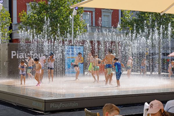 Kinder im Sommer spielen in einem Brunnen.