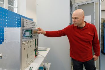 Fotografie: Ein Mitarbeiter drückt einen Schalter an dem Testgerät, mit dem die Funktionen der Verkehrssteuerung vorab überprüft werden können.