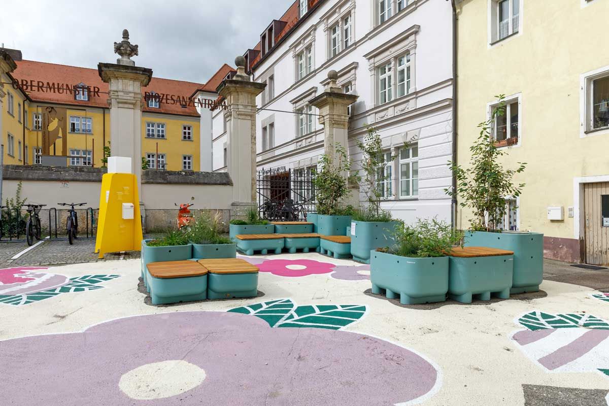 Fotografie: Bepflanzte Sitzgelegenheiten, sogenannte CityDecks, sorgen seit Mai 2025 entlang der Obermünsterstraße oder wie hier am Obermünsterplatz für mehr Grün und laden zum Verweilen ein.