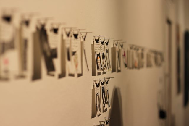 Fotografie, Kunstwerke im Postkartenformat hängen an einer Schnur